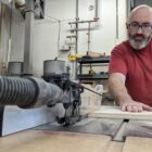 Close up at Maker Cube in Langley, BC, a member running plywood through a SawStop 3 hp cabinet table saw with proper alignment and support