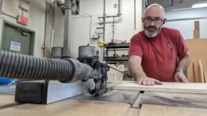 Close up at Maker Cube in Langley, BC, a member running plywood through a SawStop 3 hp cabinet table saw with proper alignment and support