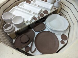 Inside the kiln at Maker Cube in Langley, BC, multiple shelves loaded with pottery pieces ready for bisque and glaze firing