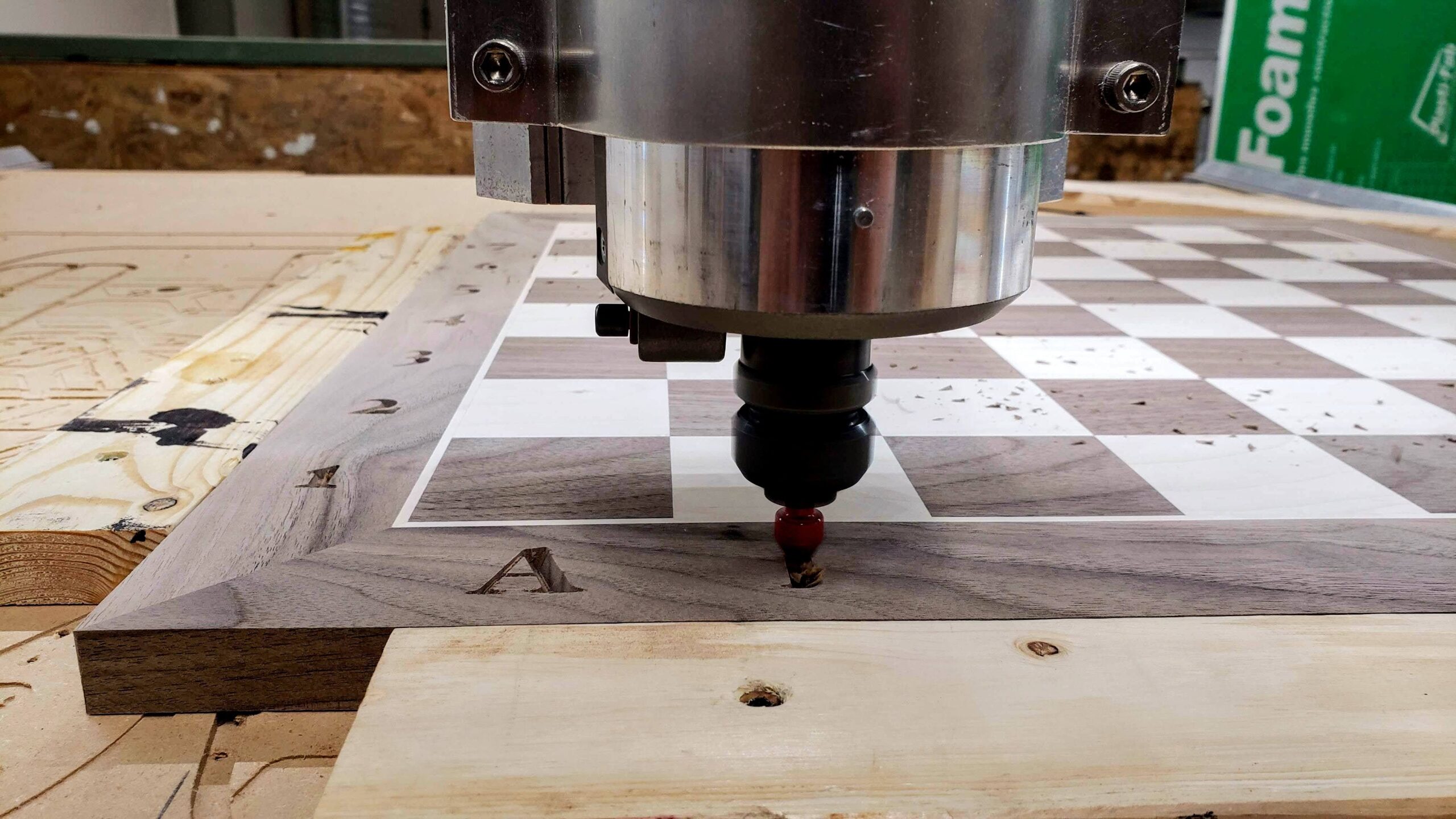 Close up of a CNC router at Maker Cube in Langley, BC, engraving lettering along the border of a large hardwood chessboard