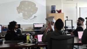Wide shot of Maker Cube’s computer lab in Langley, BC, instructor Adam speaking to several participants with Fusion 360 projected on the wall