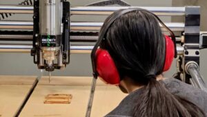 Over the shoulder photo of a participant at Maker Cube in Langley, BC, operating the CNC router while small hardwood boxes are milled
