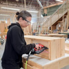 Participant using a nail gun to assemble a cedar planter box in a woodworking class at Maker Cube Langley BC