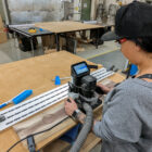 Woman using Shaper Origin handheld CNC to engrave a large wood slab in a woodworking shop in Langley BC