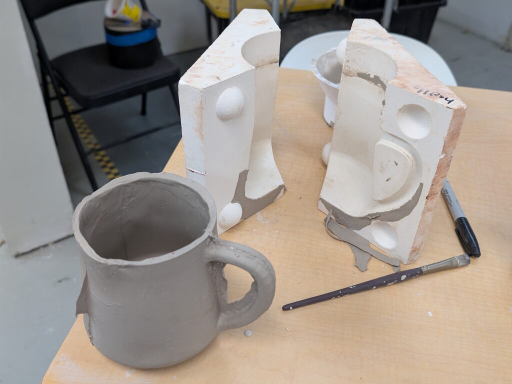 Slip cast ceramic piece beside plaster mold after demolding