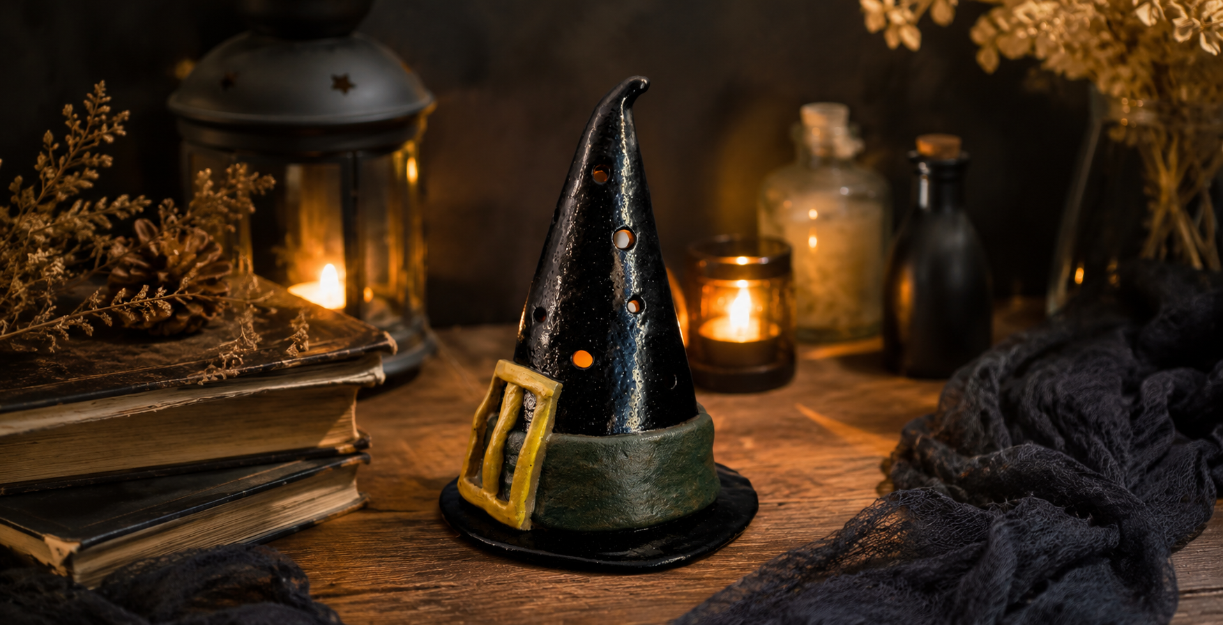 Handmade ceramic witch’s hat luminary glowing from within against a Halloween and fall themed background, for a pottery class at Maker Cube in Langley, BC